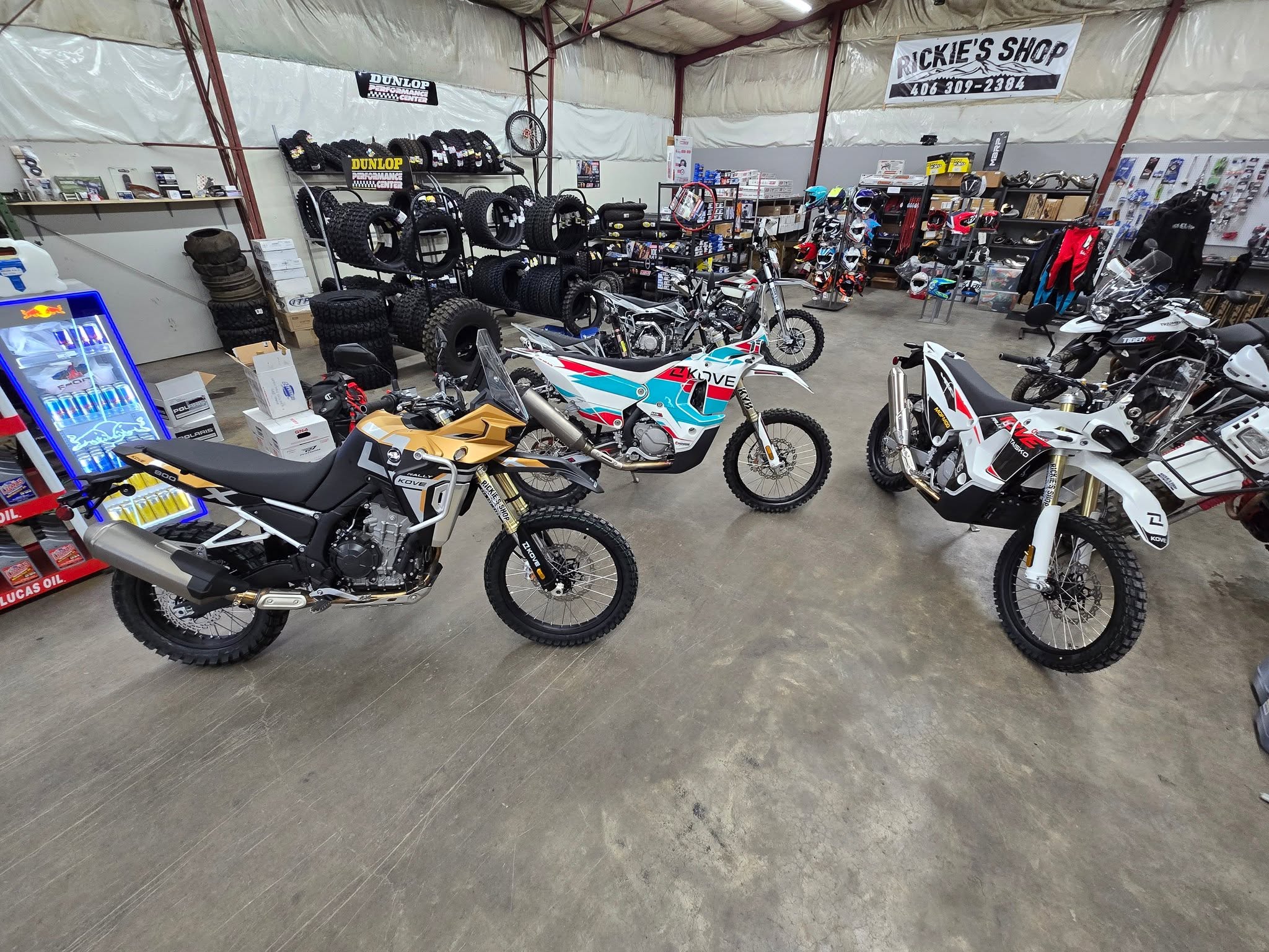 Three motorcycles staged in a row under the Rickie's Shop banner